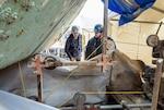 Todd Bolden, work lead, Shop 11/17, Shipfitter, Forge and Sheet Metal, and Chase Evans, general worker, Shop 75, IRR Ship Dismantling, monitor a wire saw, March 20, 2024, while cold-cutting a four-foot wide section of Caisson 3's keel in Dry Dock 3 at Puget Sound Naval Shipyard & Intermediate Maintenance Facility in Bremerton, Washington. (U.S Navy photos by Wendy Hallmark)