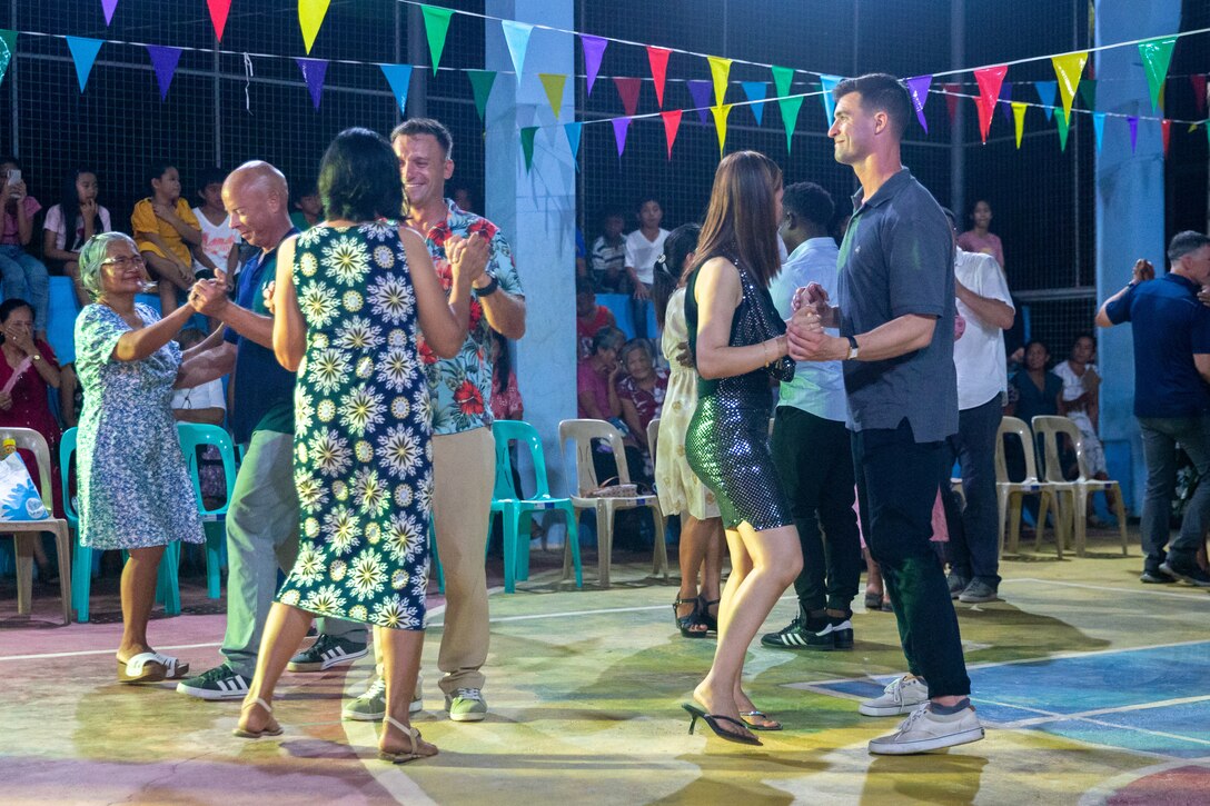 U.S. Marine Corps Sgt. Maj. Kevin Hopkins, left, the sergeant major of Marine Wing Support Squadron 174, Lt. Col. Matthew Schultz, center, the commanding officer of Marine Wing Support Squadron 174 and Maj. Randall Gregorius, a logistics officer with Marine Wing Support Squadron 174, dance with residents of Lal-lo at a ‘Barangay Fiesta’ held during Exercise Balikatan 24 at Dagupan Barangay Hall, Lal-lo, Cagayan, Philippines, April 24, 2024. BK 24 is an annual exercise between the Armed Forces of the Philippines and the U.S. military designed to strengthen bilateral interoperability, capabilities, trust and cooperation built over decades of shared experiences. (U.S. Marine Corps photo by Cpl. Trent A. Henry)