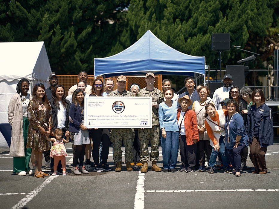 Command Master Chief Dennis Hunt, the installation command master chief, poses with the awardees, CFA Yokosuka Fleet and Family Support Center staff, and guests with a check during the 2024 Volunteer Appreciation Celebration April 25, 2024 outside the Commodore Matthew C. Perry General Mess.