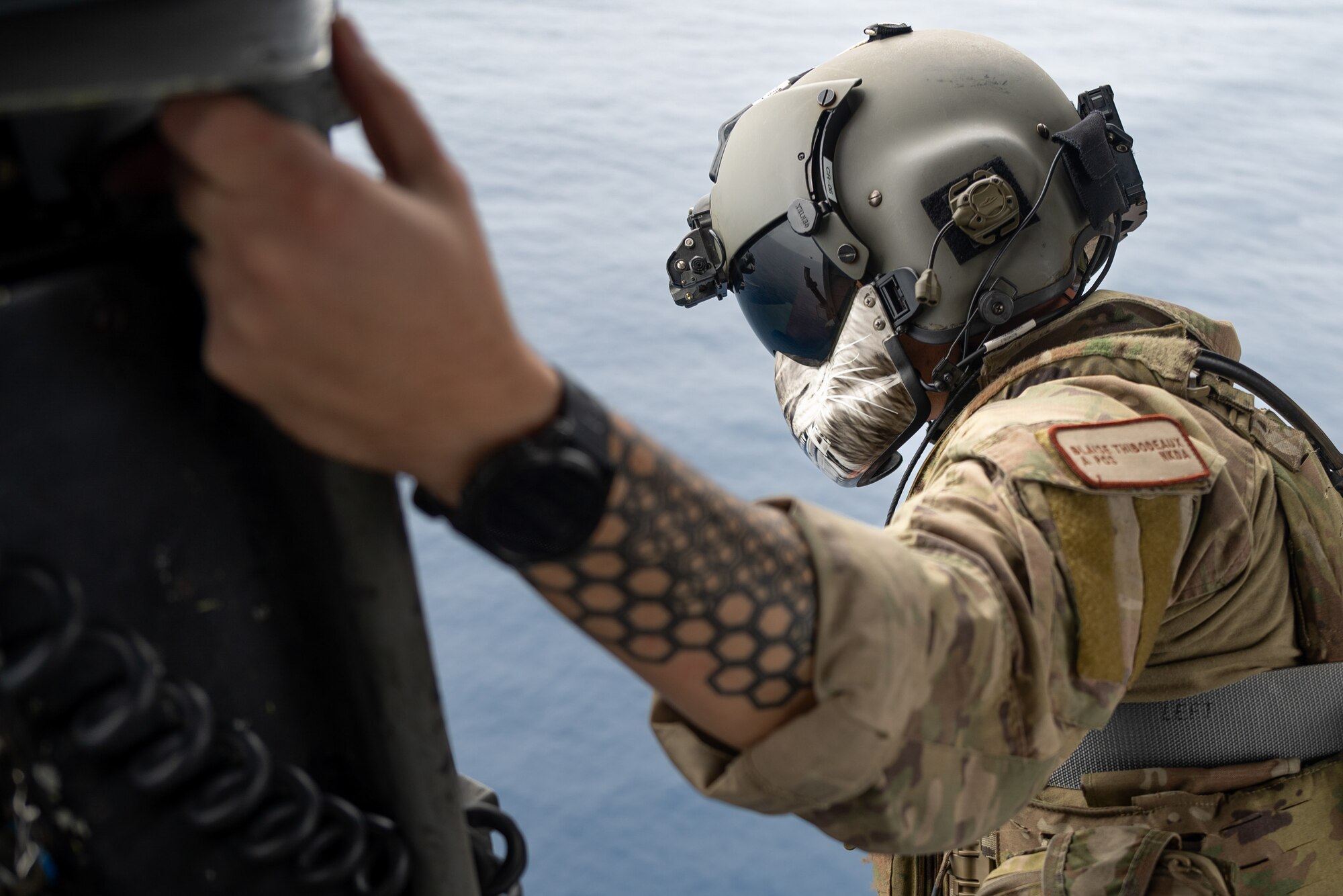 U.S. Air Force Senior Airman Blaise Thibodeaux, 33rd Rescue Squadron special missions aviator, looks out over the Pacific Ocean during a formation flight off the coast of Okinawa, Japan, April 16, 2024.