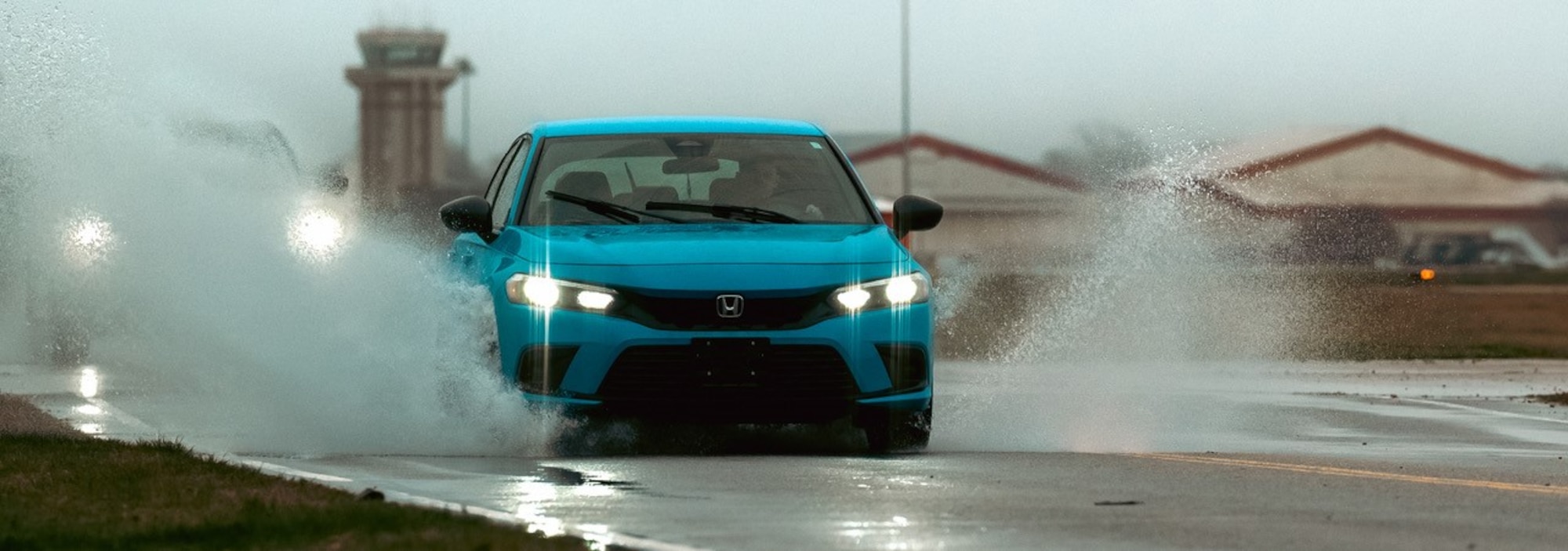 A vehicle drives through a puddle on the road.