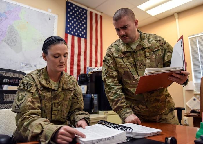 Tech. Sgt. Nikki Walberg, 455th Air Expeditionary Wing Legal Office Superintendent (left), looks over the Manual for Courts-Martial guide with Staff Sgt. Alec Knoles, NCO-in-Charge of General Law, at Bagram Air Field, Afghanistan, Mar. 17, 2016.