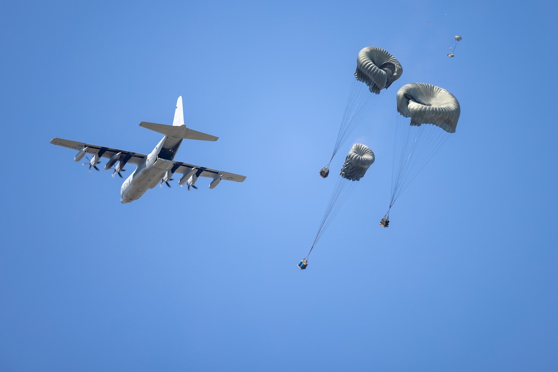 A U.S. Marine Corps C-130 flies overhead, dropping cargo during an air delivery training in Surf City, North Carolina, April 26, 2024. 2nd DSB conducted the training to evaluate their Marines' combat effectiveness and enhance air delivery skills in a controlled environment to better prepare the unit for future operations. (U.S. Marine Corps photo by Lance Cpl. Jessica J. Mazzamuto)