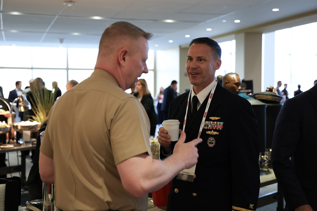 Two men eat breakfast and chat. Both are wearing Navy uniforms.