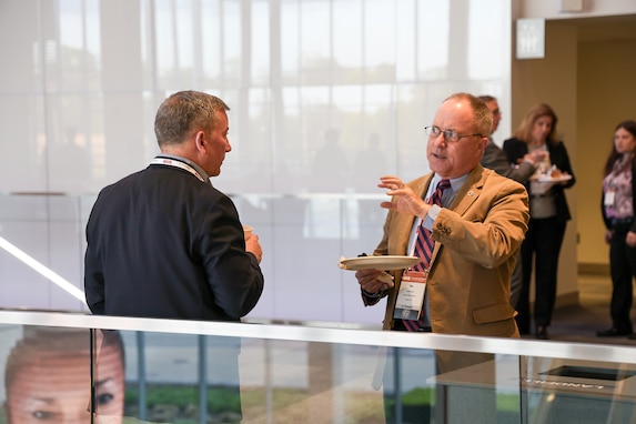 Two men eat breakfast and chat. Both are wearing business attire.