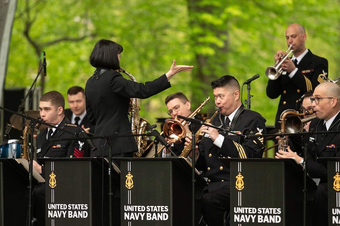 A saxophonist directs the wind and brass section of a military band.
