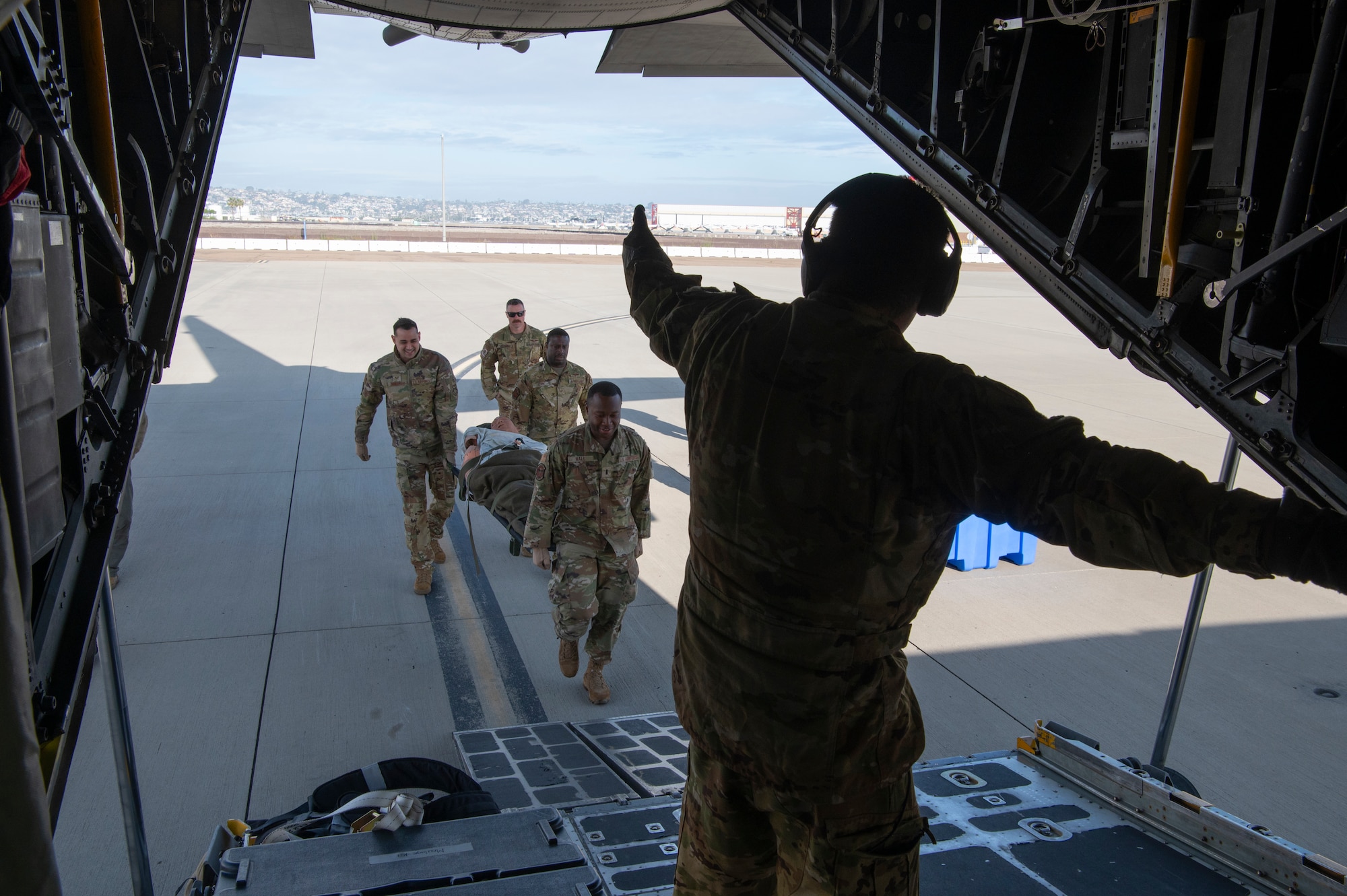 people in military uniforms carry a medical litter off of an airplane