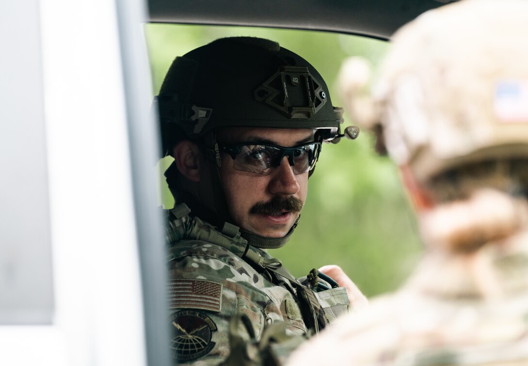 An a man in an Air Force uniform gazes at another Airman