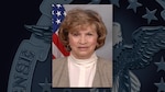 A portrait of Carol O'Leary with an American flag behind her on a background with the DLA emblem
