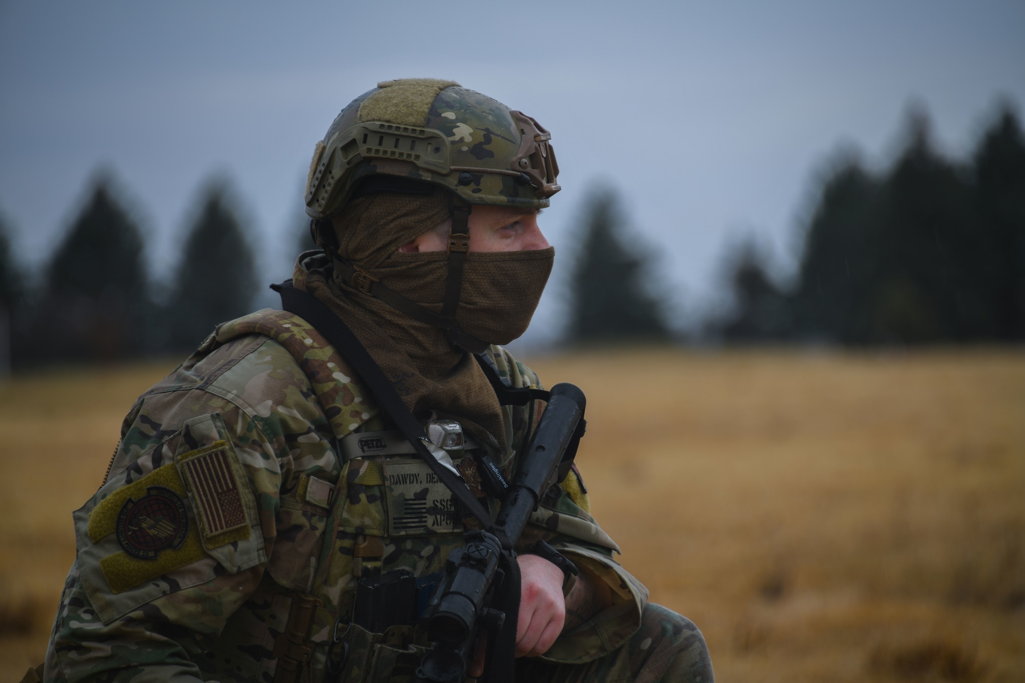 Armed military member scans area outside.