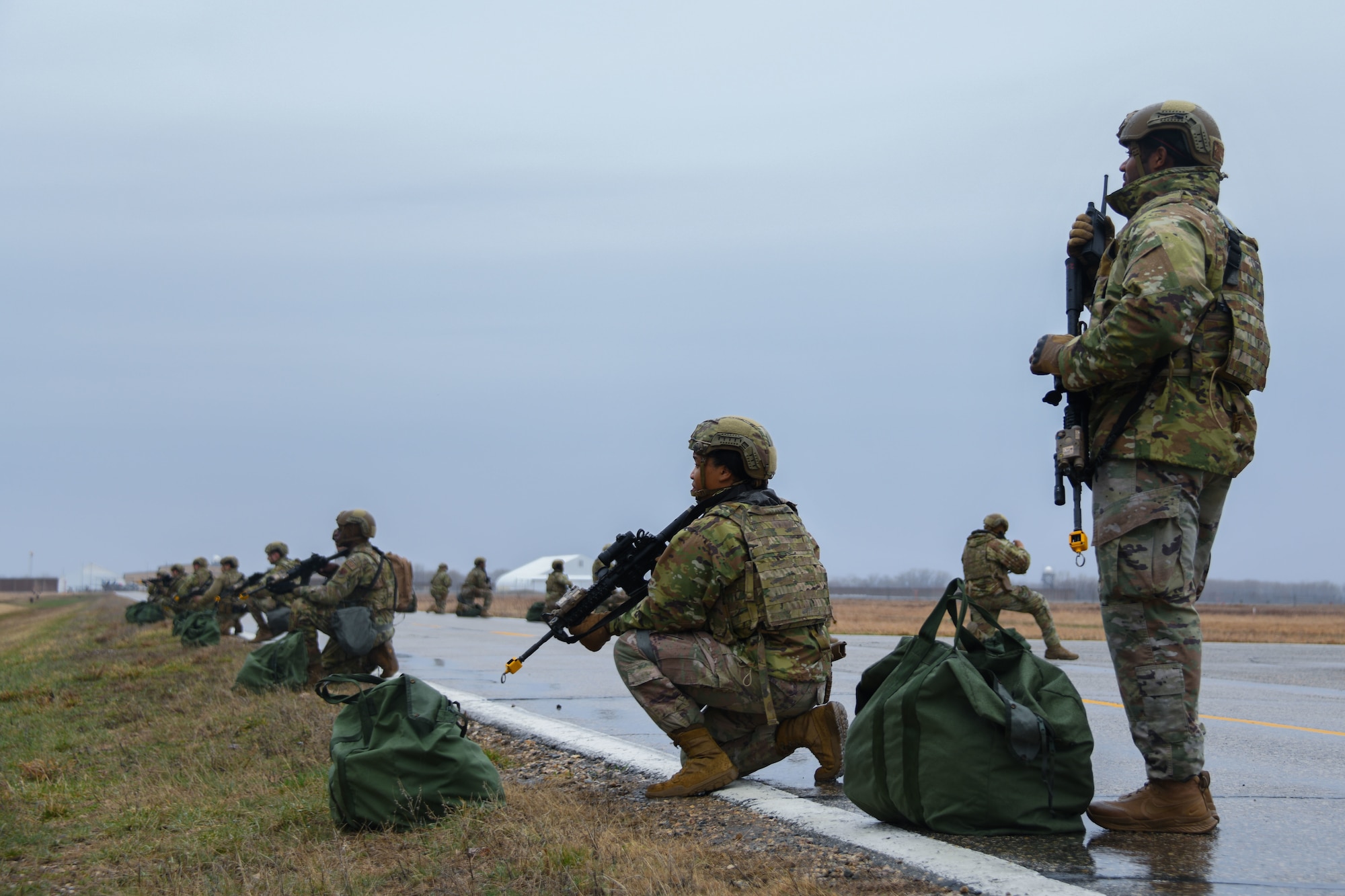 Armed military members scan area while on road.