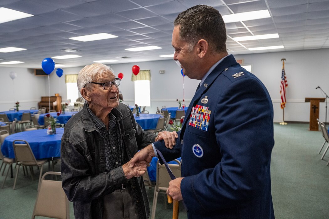 James Herring, a retired U.S. Air Force chief master sergeant and WWII veteran, left, speaks with U.S. Air Force Col. Bobby Buckner, 23rd Maintenance Group commander