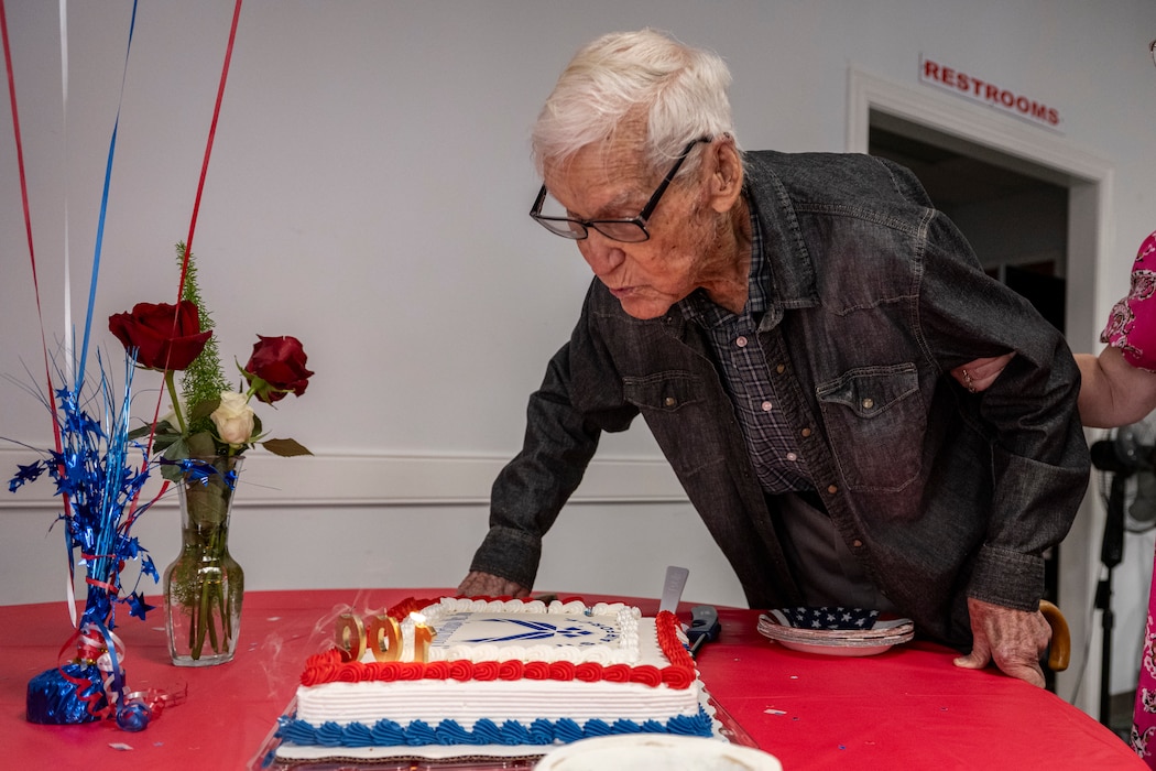 James Herring, a retired U.S. Air Force chief master sergeant and WWII veteran, blows out the candles on his cake