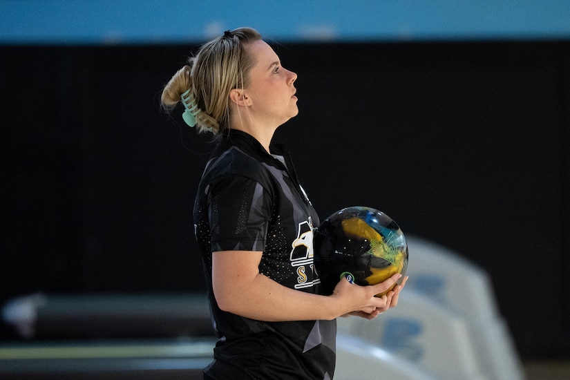 A person holds a bowling ball in preparation to bowl.
