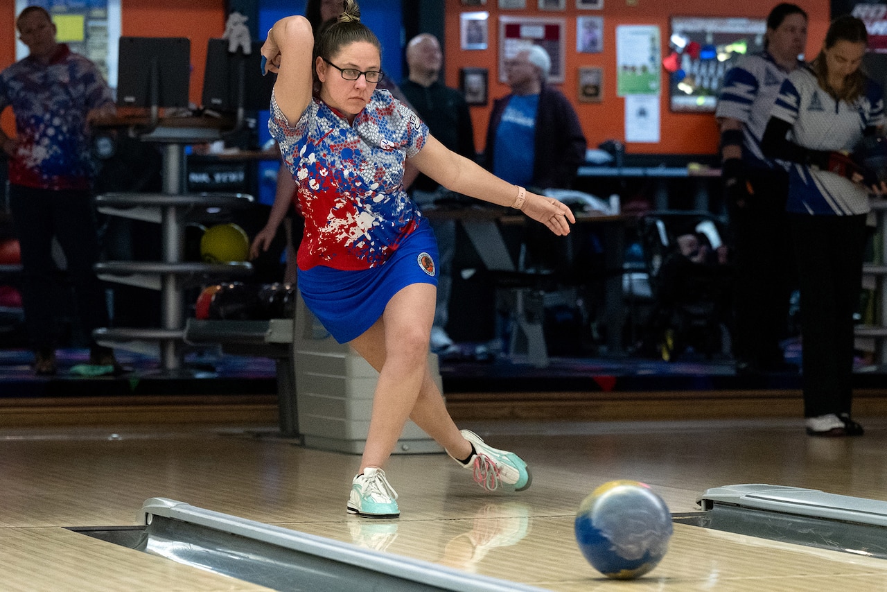 A bowler releases a bowling ball down a bowling lane.