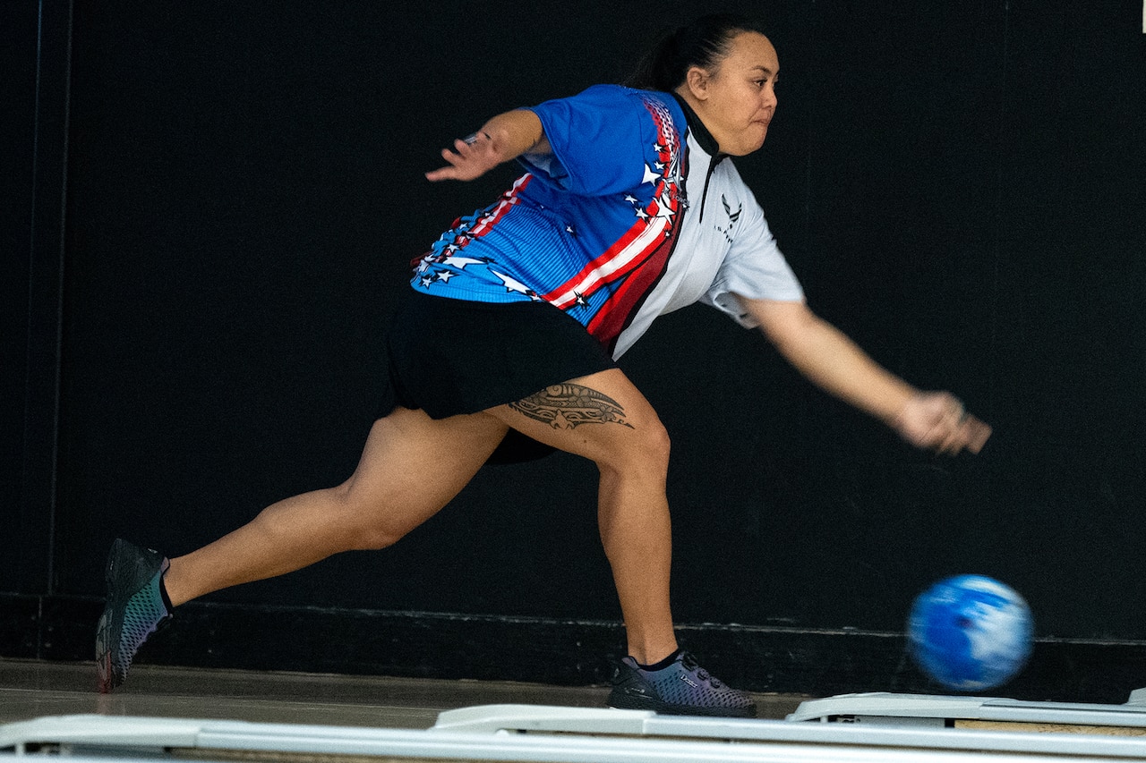 Side view of a bowler releasing a bowling ball down a bowling lane.