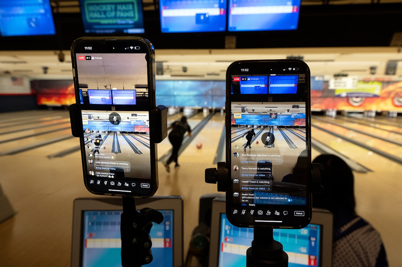 View of two mobile devices live streaming a bowling match at a bowling alley.