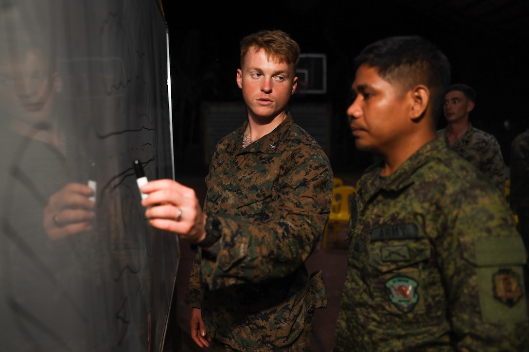 U.S. Marine Corps Cpl. Dakota Jacobs, left, a squad leader with Echo Company, 2nd Battalion, 1st Marine Regiment, 1st Marine Division, participates in a tactical decision-making game with Armed Forces of the Philippines service members during Marine Exercise 2024 near Cotabato City, Mindanao, Philippines, April 14, 2024.