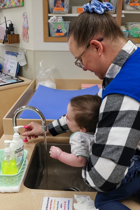 Debbie Kehishian, 9th Force Support Squadron Child Development Center (CDC) infant classroom lead teacher, washes the hands of an infant in the CDC at Beale Air Force Base, California, March 14, 2024.