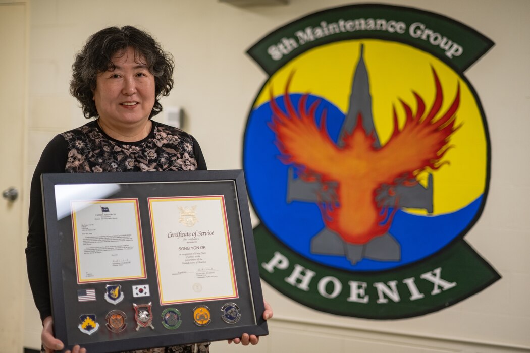 Yon Ok Song, 8th Maintenance Group maintenance system specialist, holds a framed certificate awarded to her for her 40 years of service at Kunsan Air Base, Republic of Korea