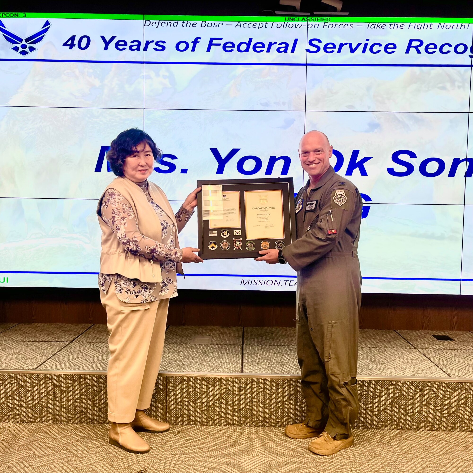 Col. Matthew Gaetke, 8th Fighter Wing commander, right, awards Yon Ok Song, 8th Maintenance Group maintenance system specialist, a certificate for her 40 years of service at Kunsan Air Base, Republic of Korea
