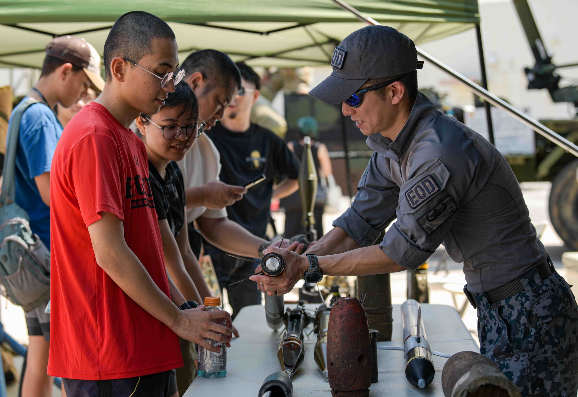A Japan Air Self Defense Force Airman teaches America Fest attendees about a simulated ordnance.