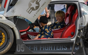 America Fest attendees sit behind the wheel of a modified sports car.