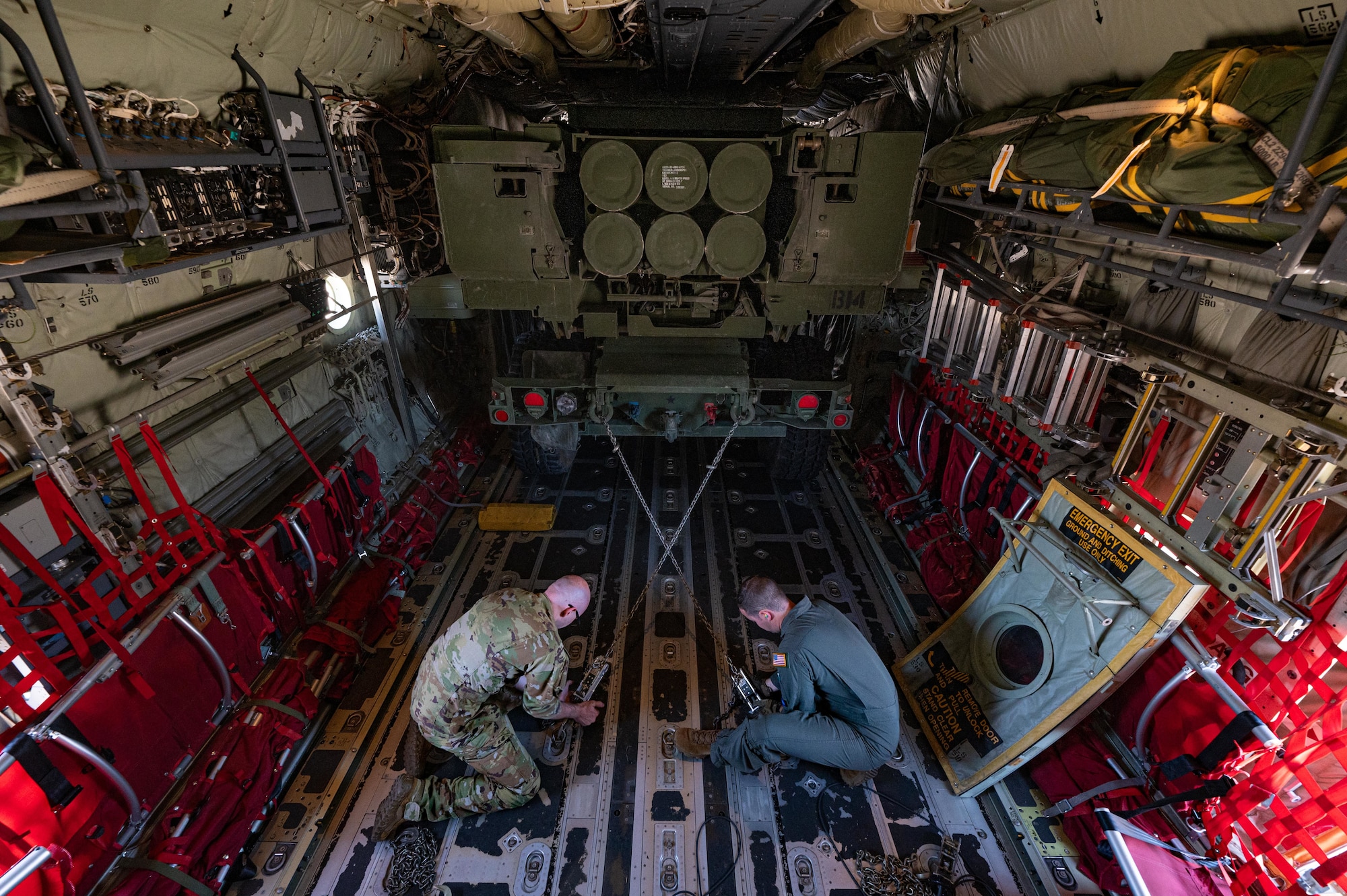 U.S. Air Force Maj. Riley Miller, 37th Airlift Squadron C-130J Super Hercules pilot, and USAF Tech. Sgt. Hayden Thomas, 37th AS loadmaster, tie down a U.S. Army National Guard M142 High Mobility Artillery Rocket System (HIMARS), from the 133rd Field Artillery Regiment, into a C-130J at Chievres Air Base, Belgium, July 29, 2024.