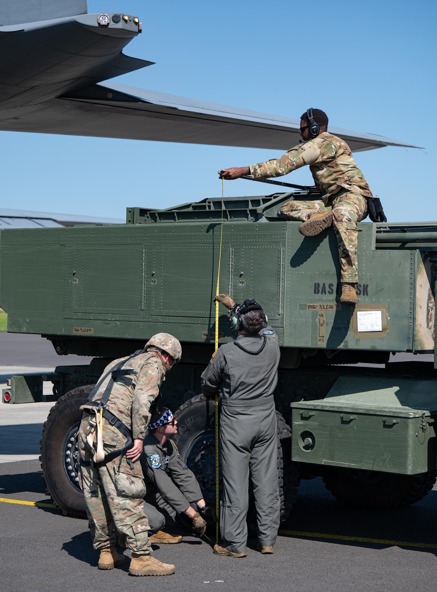 U.S. Air Force 37th Airlift Squadron C-130J Super Hercules loadmasters and U.S. Army National Guard 4th Battalion, 133rd Field Artillery Regiment M142 High Mobility Artillery Rocket System (HIMARS) crewmembers measure the vehicle height before loading it into a C-130J, at Chievres Air Base, Belgium, July 29, 2024.