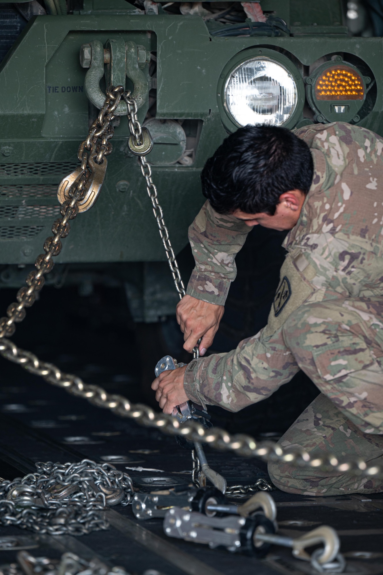 U.S. Army Spc. James Robinson, 4th Battalion,133rd Field Artillery Regiment M142 High Mobility Artillery Rocket System (HIMARS) crewmember, ties down the 38,000 pound-vehicle on a U.S. Air Force C-130J Super Hercules, at Chievres Air Base, Belgium, July 29, 2024.