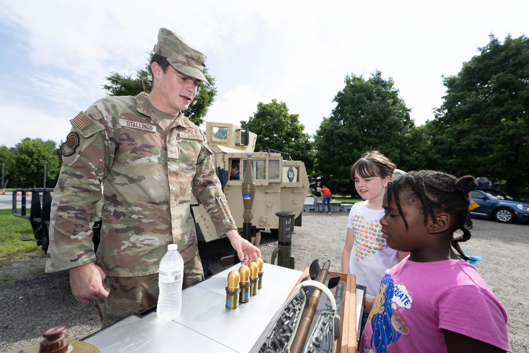 U.S. Air Force Airman 1st Class Carter Stallings, 436th Civil Engineer Squadron explosive ordnance apprentice, shows children training models of equipment during a Touch a Truck event in Dover, Delaware, July 31, 2024. Touch a Truck is part of the Dover Public Library summer reading program and invites children to learn about various work vehicles. (U.S. Air Force photo by Mauricio Campino)