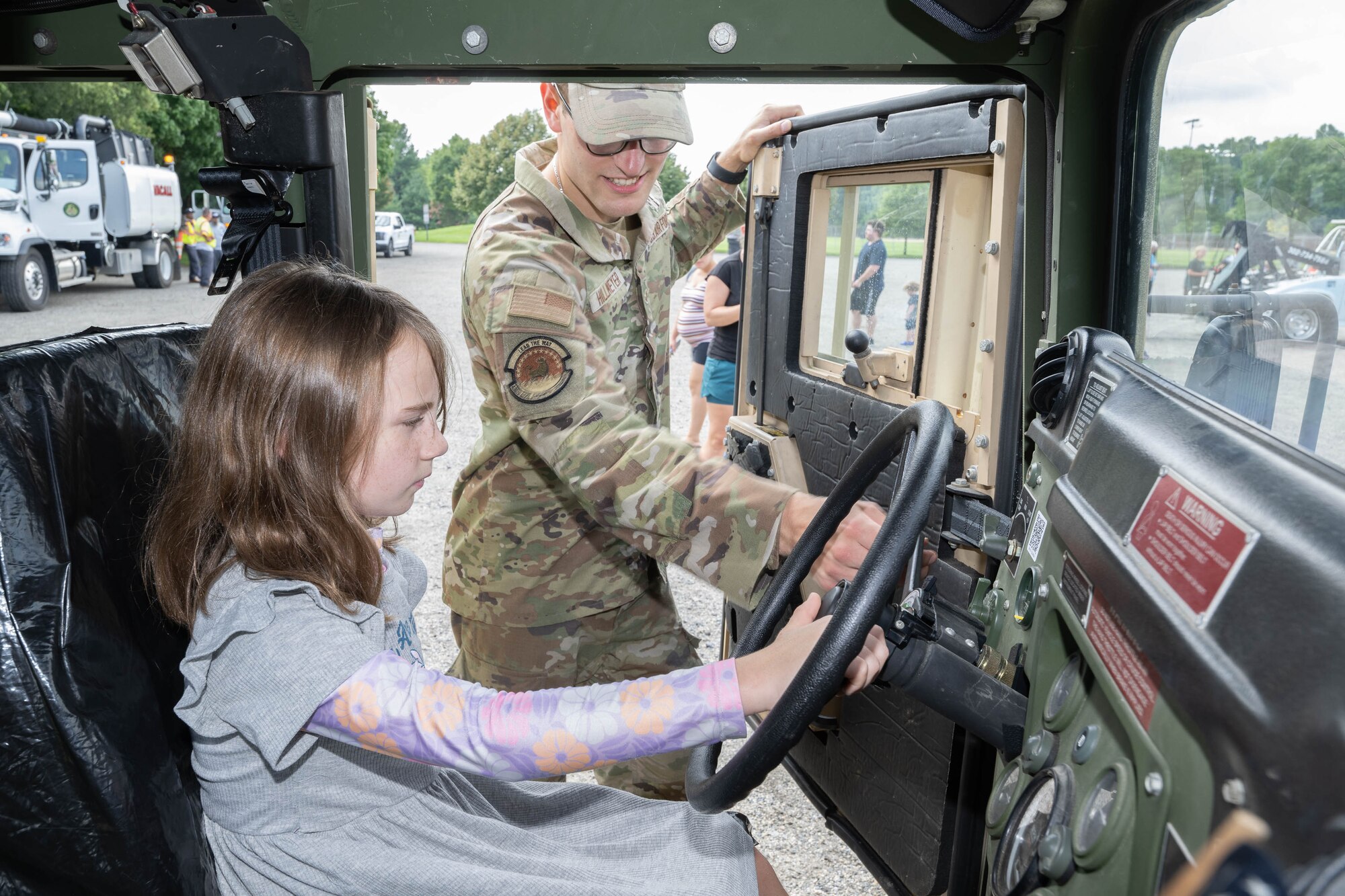 U.S. Air Force Airman 1st Class Luca Hillmeyer, 436th Civil Engineer Squadron explosive ordnance apprentice, shows children the inside of an EOD Humvee during a Touch a Truck event in Dover, Delaware, July 31, 2024. Touch a Truck is part of the Dover Public Library summer reading program and invites children to learn about various work vehicles. (U.S. Air Force photo by Mauricio Campino)