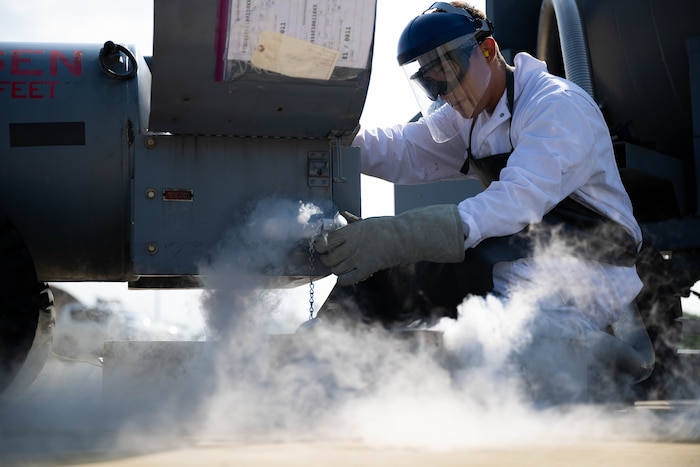 Fuels facilities specialist, transfers liquid oxygen into a beaker.