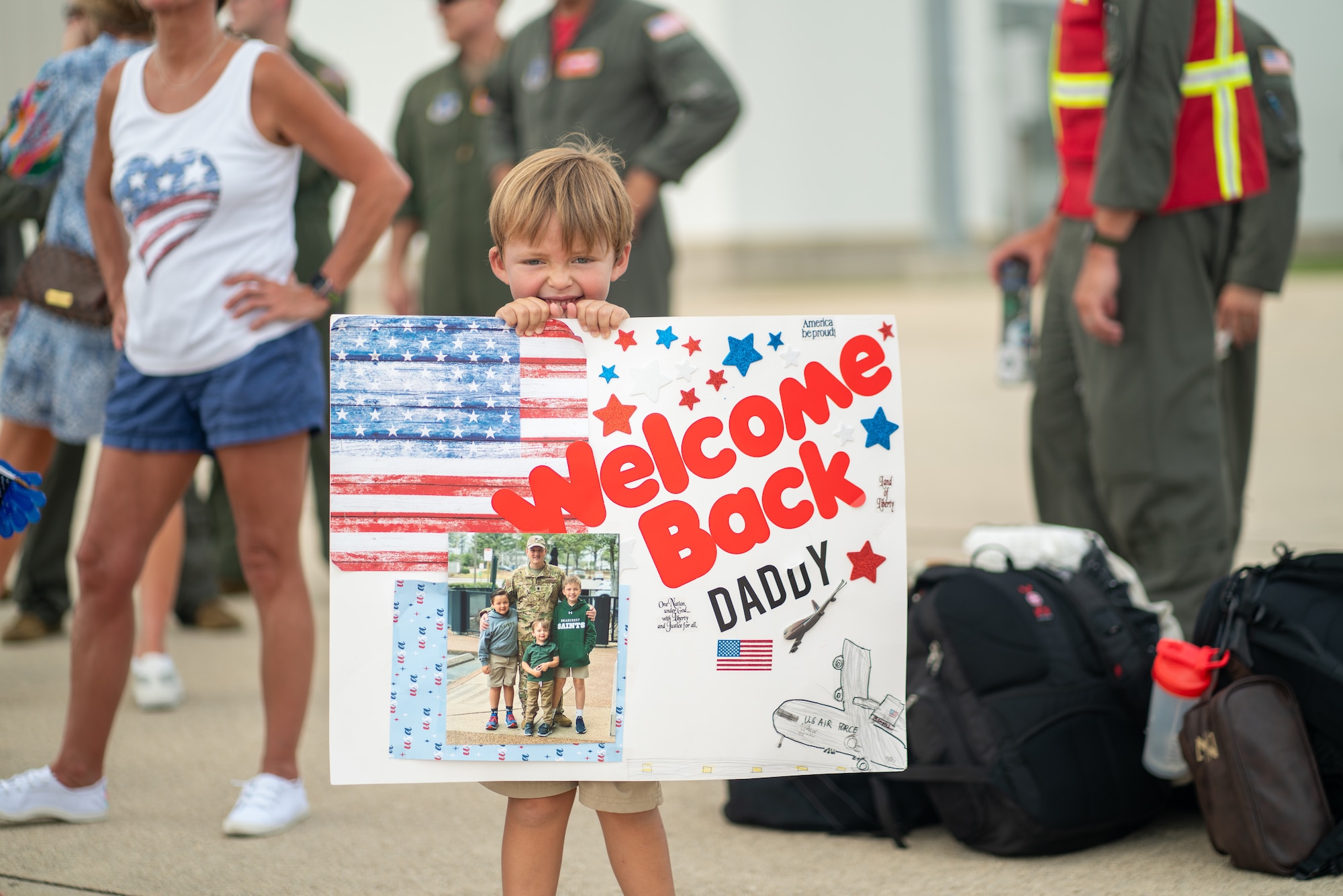 Airmen and civilians gather in front of a hangar.
