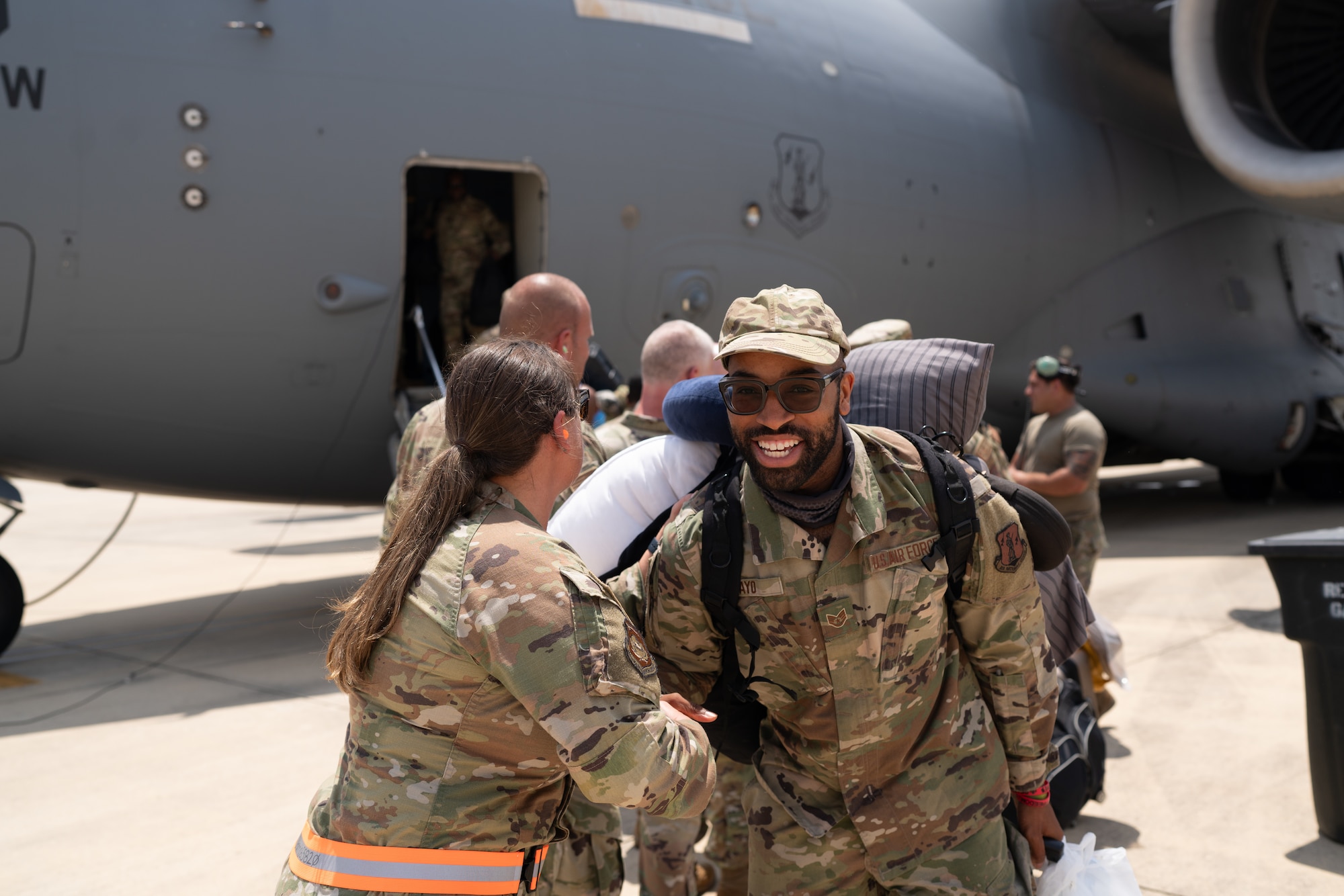 A male and a female airman shake hands in front of a plane.