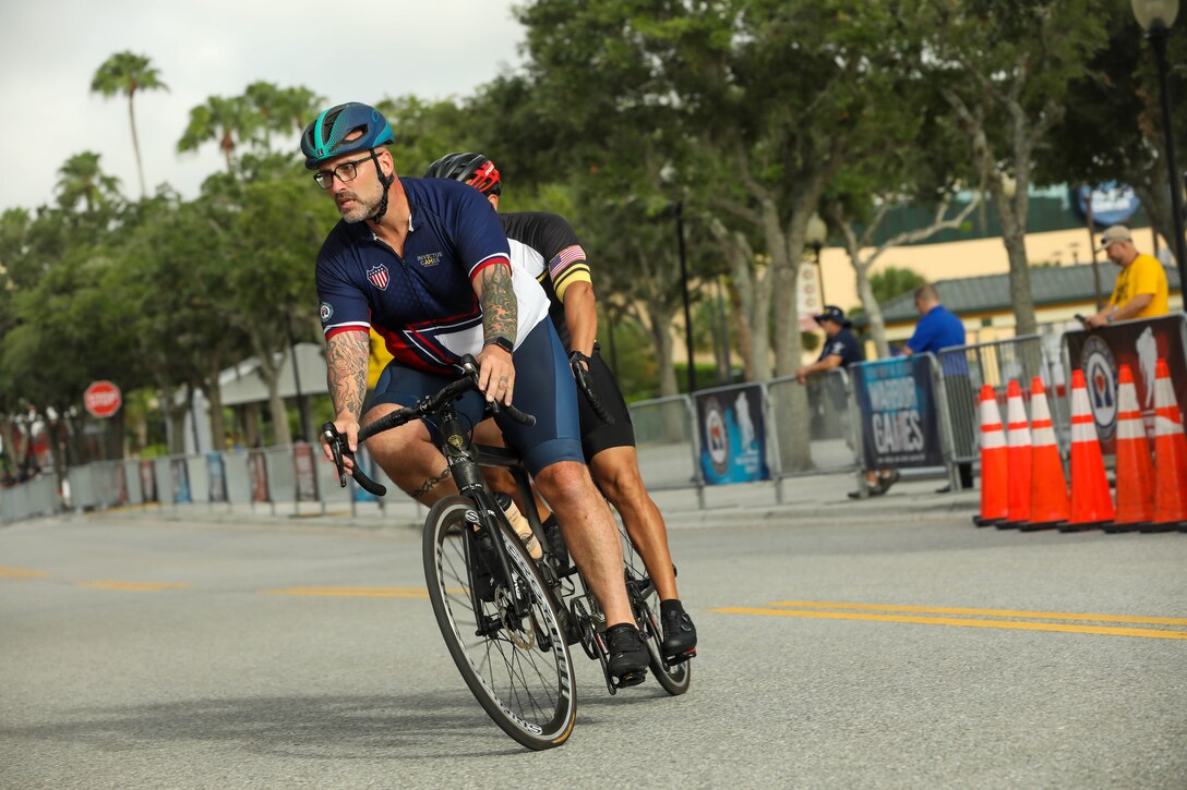Team Army coach Greg Quarles rides the tandem bike with U.S. Army veteran Henry Escobedo at cycling familiarization during the 2024 Department of Defense Warrior Games