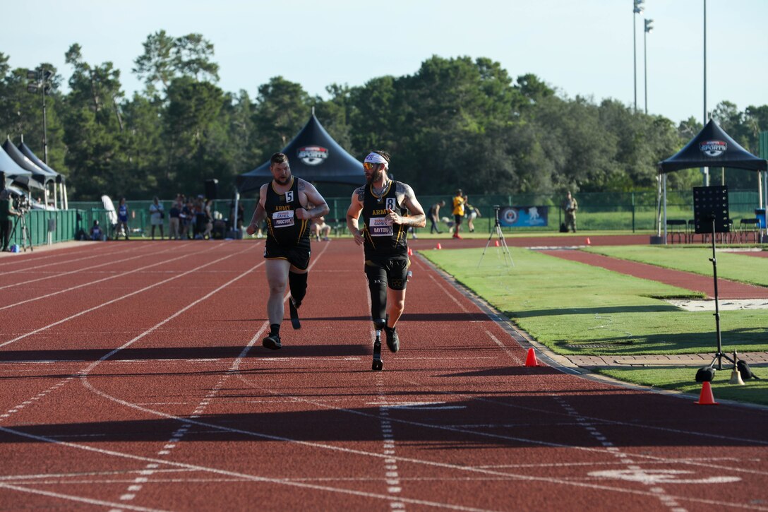 U.S. Army Staff Sgt. Adam Proctor, left, and veteran Patrick Dayton run together at the track event during the 2024 Department of Defense Warrior Games