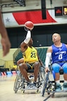 U.S. Army Staff Sgt. Derrick Thompson prepares to pass the ball to a teammate in a wheelchair basketball game during the 2024 Department of Defense Warrior Games
