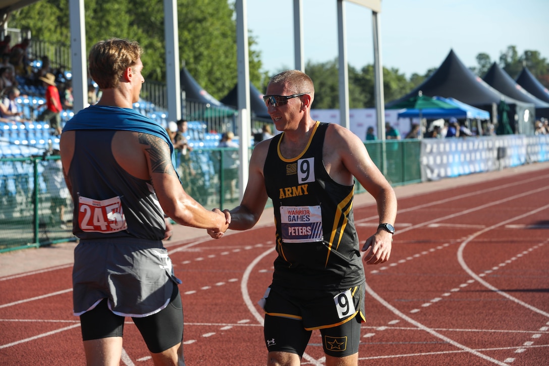 U.S. Army Sgt. 1st Class Jeffrey Peters shakes hands with a Team SOCOM athlete after a race at the track event during the 2024 Department of Defense Warrior Games