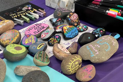 A collection of painted rocks with motivational messages is displayed on a table.