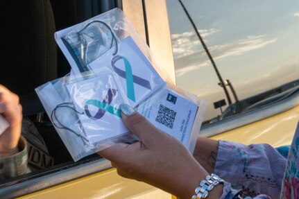 A person holds packaged ribbons up to a car window.