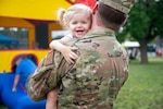 An airman holds a smiling young girl.