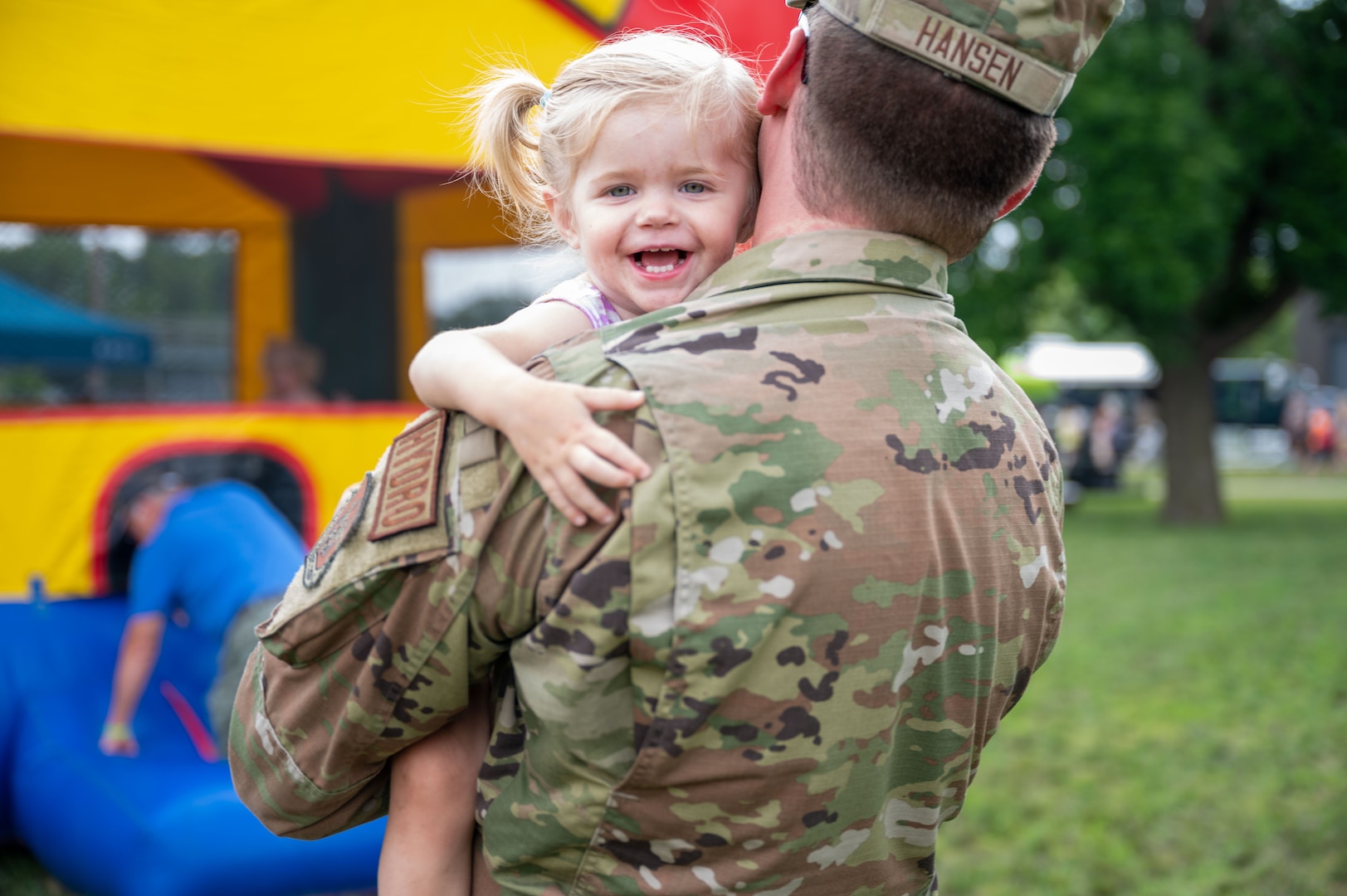 An airman holds a smiling young girl.