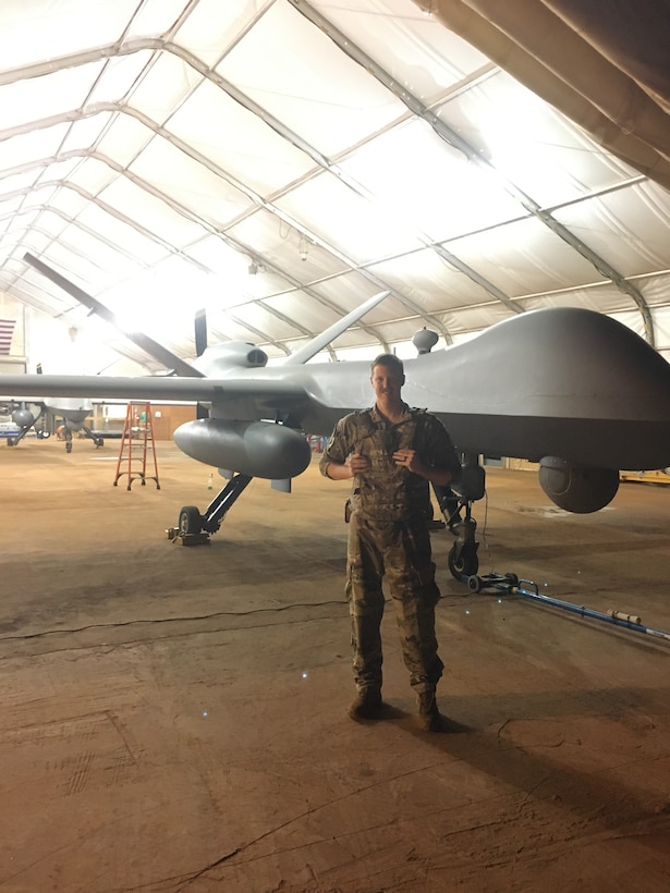 An Airman stands in front of an RPA