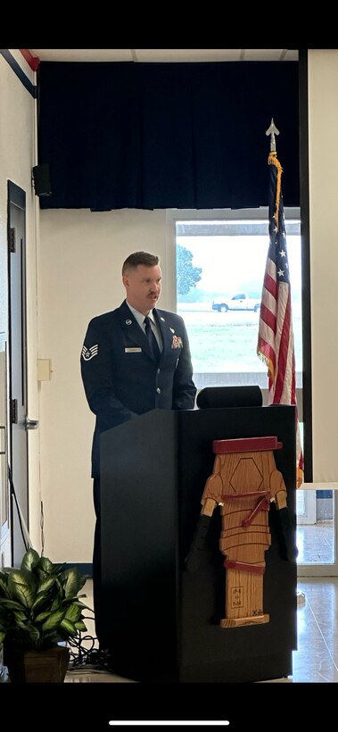 An Airman in dress blues stands behind a podium