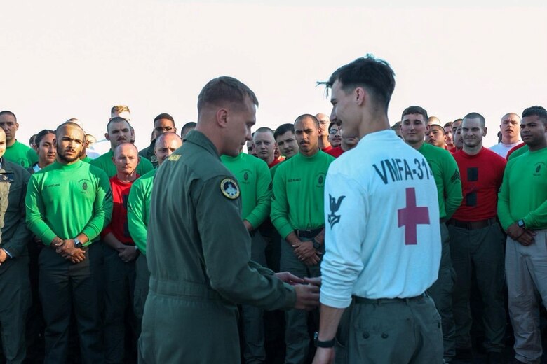 Lt. Col. Jeffrey Davis, left, commanding officer of Marine Fighter Attack Squadron 314, awards the commanding officer coin for excellence to Hospital Corpsman 2nd Class Bryce Donovan aboard the flight deck of the Nimitz-class aircraft carrier USS Abraham Lincoln (CVN 72), July 20, 2024, while underway in the Pacific Ocean. VMFA 314, assigned to Carrier Air Wing 9 aboard the Lincoln, is underway conducting routine operations in the U.S. 7th Fleet area of operations. (U.S. Marine Corps courtesy photo)