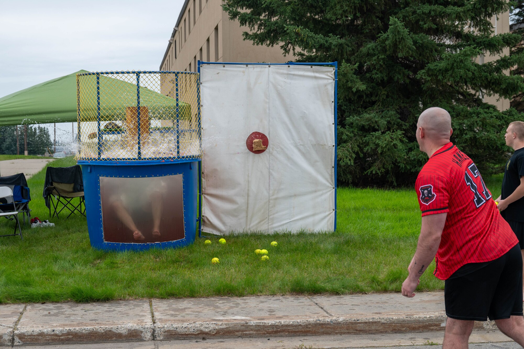 U.S. Air Force Master Sgt. Daniel James (right), 354th Logistics Readiness Squadron fuel service flight chief, throws a softball at a dunk tank button to dunk 2nd Lt. Cody Wells, 354th LRS vehicle management flight commander