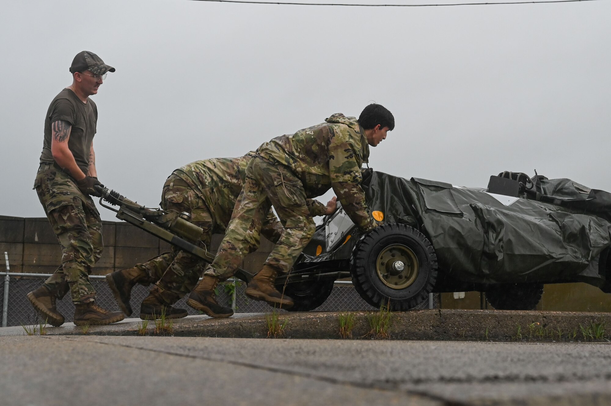 Senior Airman Johnathon Clark, left, 8th Logistics Readiness Squadron packing and crating supervisor, Staff Sgt. Dylan Tusano, middle, 8th LRS noncommissioned officer in charge of inbound cargo, and Senior Airman Ryan Cimino, right, 8th LRS inbound cargo technician, push a bomb loader up a ramp during a cargo deployment function.