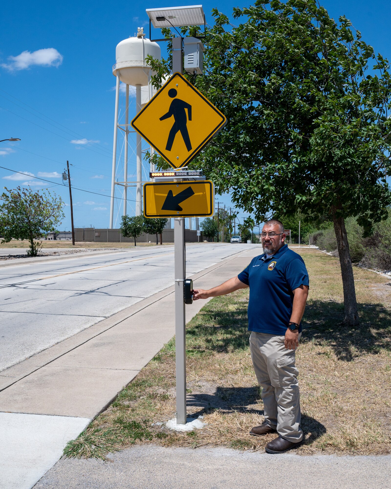 Alexander Valdez, 47th Flying Training Wing occupational safety manager, presses the button of a newly installed crosswalk sign at Laughlin Air Force Base, Texas, June 17, 2024. The installation of these signs increases pedestrian safety on base, bringing more attention to the presence of Airmen who are walking or jogging along the trail by Losano Fitness Center. (U.S. Air Force photo by Staff Sgt. Nicholas Larsen)