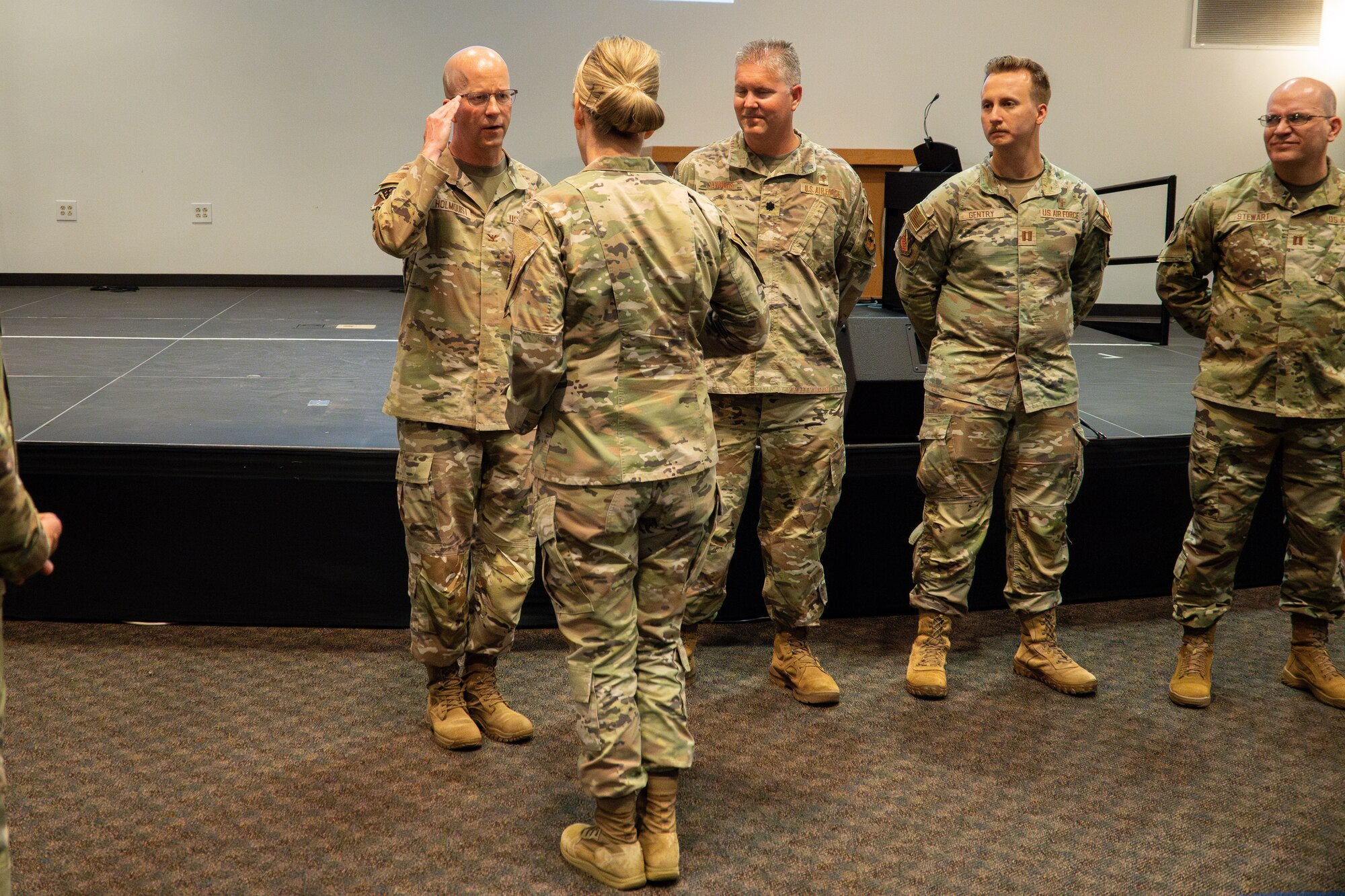 Several Airmen stand together while one renders a salute.